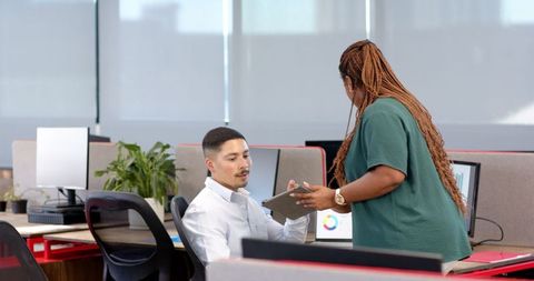 Businessman Collaborates with Colleague on Tablet in Office Environment