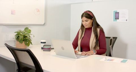 Woman working on laptop at contemporary office workspace