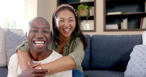 Happy Couple Embracing on Couch Laughing Together in Living Room