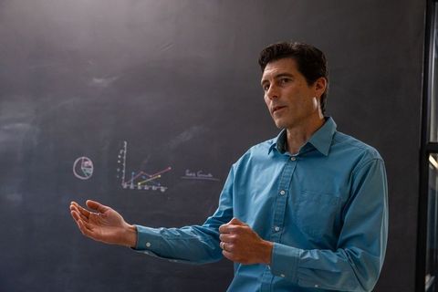 Male educator explaining chart diagrams on chalkboard