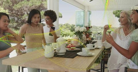 Multigenerational women enjoying afternoon tea in sunroom with garden view and desserts