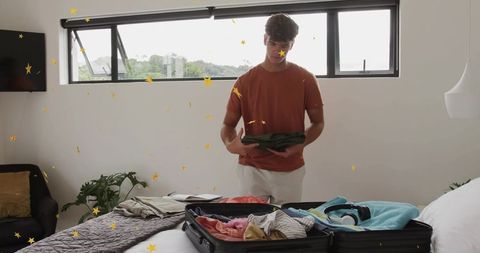Young man packing suitcase in modern bedroom preparing for trip with organized luggage