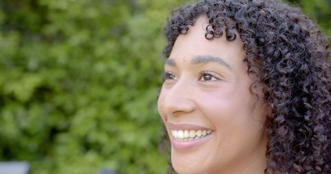 Joyful woman with curly hair enjoying outdoor garden