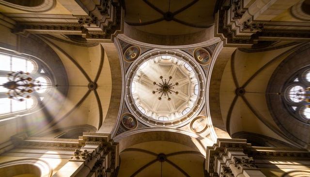 Sunlight streaming through clerestory illuminating central dome and chandelier in cathedral
