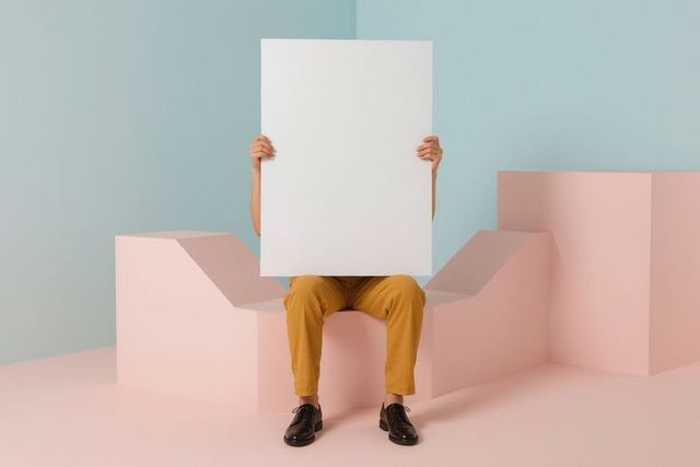 Person holding blank poster in minimalist pastel studio