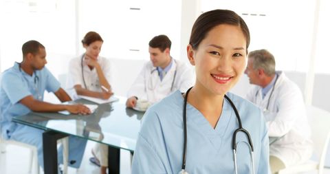 Confident Nurse with Medical Team in Background - Download Free Stock Images Pikwizard.com