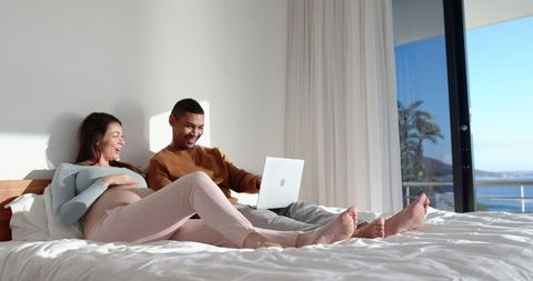 Diverse Couple Enjoying Relaxed Moment by Ocean During Pregnancy