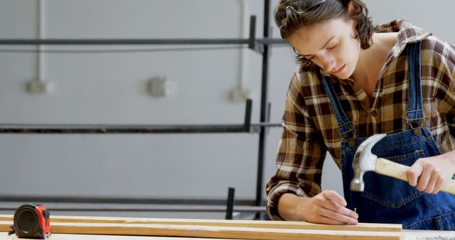 Young Woman Measuring and Hammering Wood in Workshop - Download Free Stock Images Pikwizard.com