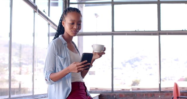 Relaxed Businesswoman Drinking Coffee and Using Smartphone by Office Window - Download Free Stock Images Pikwizard.com