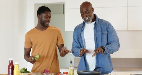 African american father and son cooking at kitchen island