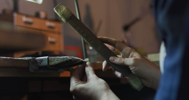 Close-up of artisan shaping metal with hand tools in a workshop. This image is ideal for illustrating themes of craftsmanship, precision, and hands-on work. Perfect for articles, advertisements, or promotional materials related to handmade products, DIY projects, and craftsmanship tutorials.