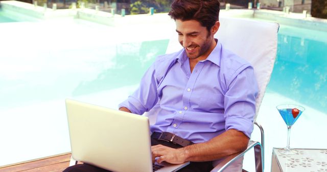 Handsome man using laptop and relaxing poolside