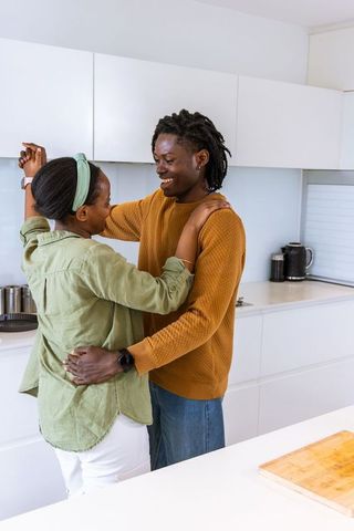 African american couple hugging and smiling in bright modern kitchen romantic home moment