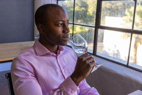 Man Holding Wine Glass Relaxing by Window in Modern Interior