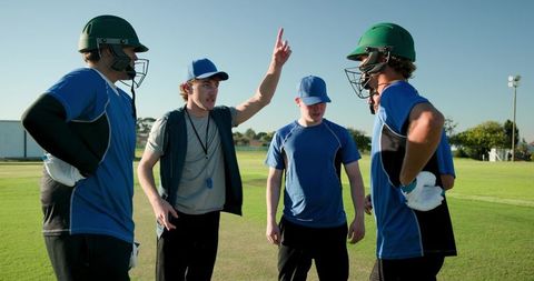 Cricket coach instructing team on field pointing strategy during outdoor training session