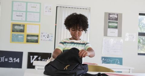 African American Student Searching Backpack in Bright Classroom Preparing for Lesson