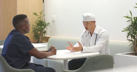 Medical consultation between doctors in modern clinical lounge discussing patient care
