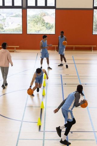 Team Practicing Dribbling Skills at Indoor Basketball Court