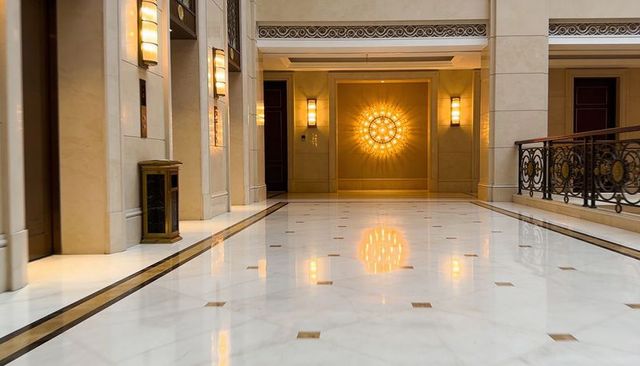 Sunburst chandelier reflecting on polished marble lobby floor in luxurious hotel