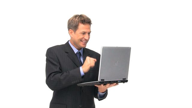 Businessman in a dark suit holding laptop with enthusiasm and smiling. Ideal for concepts related to corporate success, professional achievements, business communication, and modern technology in the workplace. Great for websites, presentations, and advertisements focusing on business environments, career advancements, and office productivity.