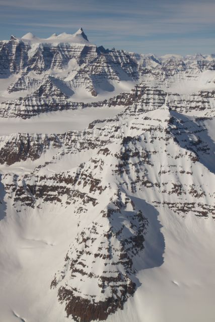 A wider view of mountains showing the distinctive geology of the Geikie Plateau region in eastern Greenland, as seen from NASA's P-3B aircraft on April 16, 2012.  Credit: NASA/GSFC/Jefferson Beck  ===========  IceBridge, a six-year NASA mission, is the largest airborne survey of Earth's polar ice ever flown. It will yield an unprecedented three-dimensional view of Arctic and Antarctic ice sheets, ice shelves and sea ice. These flights will provide a yearly, multi-instrument look at the behavior of the rapidly changing features of the Greenland and Antarctic ice.  Data collected during IceBridge will help scientists bridge the gap in polar observations between NASA's Ice, Cloud and Land Elevation Satellite (ICESat) -- in orbit since 2003 -- and ICESat-2, planned for early 2016. ICESat stopped collecting science data in 2009, making IceBridge critical for ensuring a continuous series of observations.  IceBridge will use airborne instruments to map Arctic and Antarctic areas once a year. IceBridge flights are conducted in March-May over Greenland and in October-November over Antarctica. Other smaller airborne surveys around the world are also part of the IceBridge campaign.  To read more about IceBridge - Arctic 2012 go to: <a href="http://www.nasa.gov/mission_pages/icebridge/index.html" rel="nofollow">www.nasa.gov/mission_pages/icebridge/index.html</a>   <b><a href="http://www.nasa.gov/audience/formedia/features/MP_Photo_Guidelines.html" rel="nofollow">NASA image use policy.</a></b>  <b><a href="http://www.nasa.gov/centers/goddard/home/index.html" rel="nofollow">NASA Goddard Space Flight Center</a></b> enables NASA’s mission through four scientific endeavors: Earth Science, Heliophysics, Solar System Exploration, and Astrophysics. Goddard plays a leading role in NASA’s accomplishments by contributing compelling scientific knowledge to advance the Agency’s mission.  <b>Follow us on <a href="http://twitter.com/NASA_GoddardPix" rel="nofollow">Twitter</a></b>  <b>Like us on <a href="http://www.facebook.com/pages/Greenbelt-MD/NASA-Goddard/395013845897?ref=tsd" rel="nofollow">Facebook</a></b>  <b>Find us on <a href="http://instagrid.me/nasagoddard/?vm=grid" rel="nofollow">Instagram</a></b>