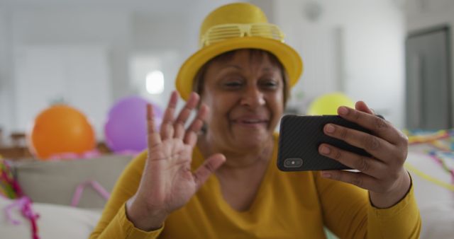 Happy african american senior woman making new year's eve smartphone image call blowing kisses. active, youthful retirement lifestyle, celebrating at home with communication.
