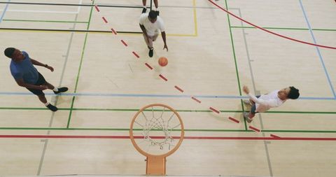Overhead action: diverse men dribbling, passing and shooting on indoor basketball court
