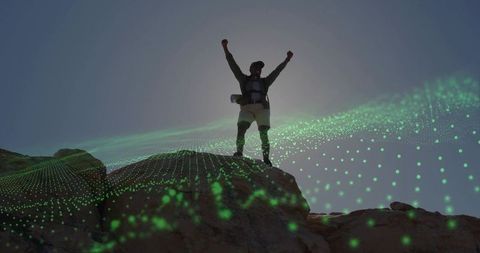 Silhouetted hiker raising arms on rocky summit with green digital mesh overlay celebrating triumph