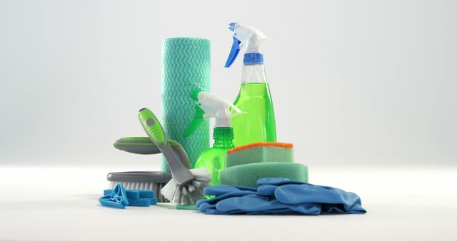 A variety of cleaning supplies, including spray bottles, sponges, brushes, and gloves, are arranged against a white background, with copy space. These items are commonly used for household chores and maintaining cleanliness.