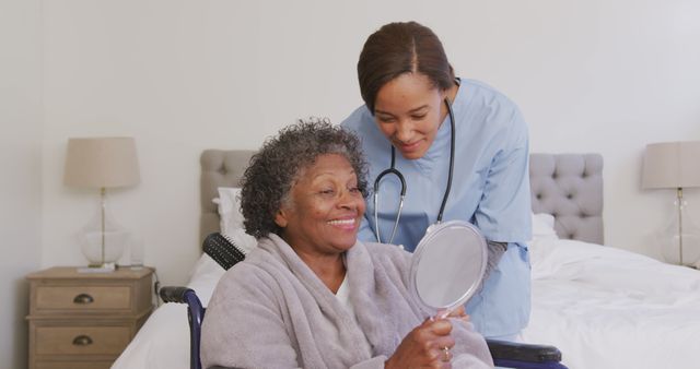 Senior african american woman sitting in wheelchair and female doctor looking at mirror. Medicine, healthcare, disability and lifestyle.
