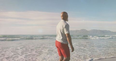 Senior Man Enjoying Tranquil Beach Walk in Soft Light