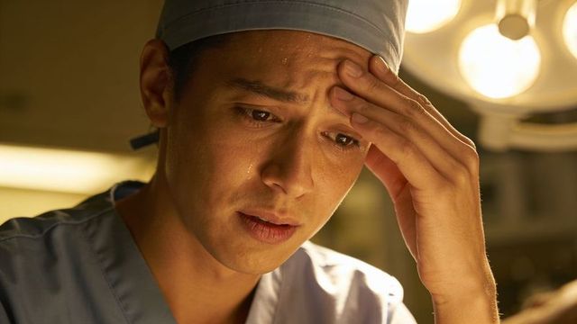 Tearful surgeon under operating lights feeling emotional during intense surgery