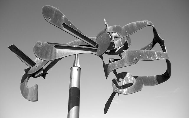Abstract metal sculpture featured against clear sky. Ideal for projects related to modern art, urban landscapes, or creativity. Can be used in educational contexts, art exhibitions, or as a decorative piece in contemporary designs.
