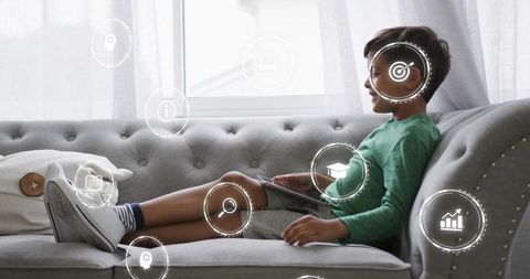 Boy relaxing on tufted sofa using tablet for online learning and educational apps
