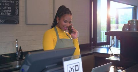 Barista taking phone order at modern cafe counter with pos and qr code