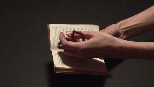 Hands are holding rosary beads over an open Bible, suggesting a moment of deep prayer and devotion. Suitable for illustrating themes related to religious studies, faith articles, Christian prayer guides, and spiritual blog posts.