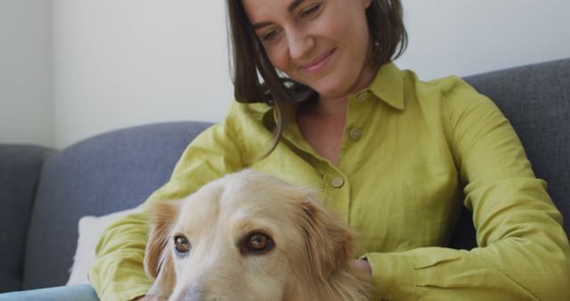 Woman in casual attire enjoying calm moment with her dog on couch at home. Ideal for themes of pet care, companionship, indoor relaxation, and domestic life.