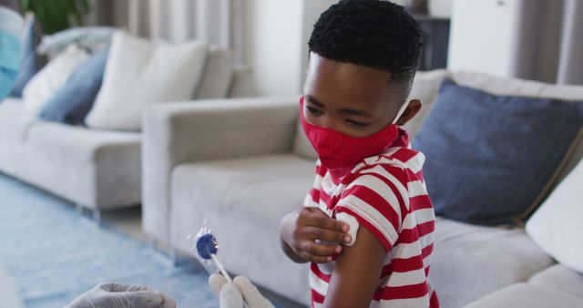 Young child receiving vaccine while wearing a red mask at home - Download Free Stock Images Pikwizard.com