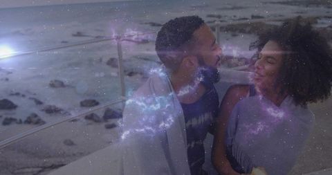 Couple embracing evening by sea with cosmic overlay