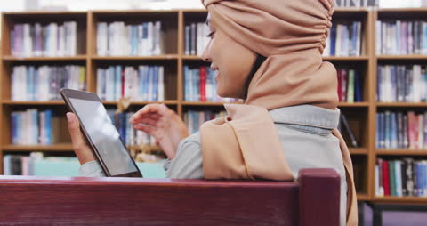 Asian Student in Hijab Using Tablet in Library