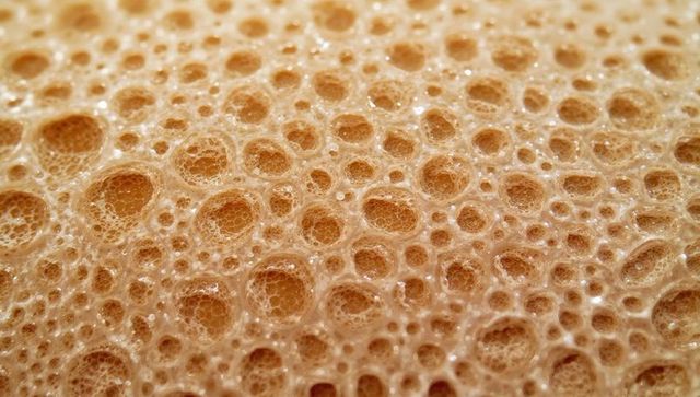 Macro crema foam honeycomb bubbles closeup texture warm caramel froth glossy surface
