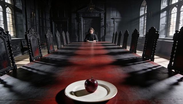 Sitting figure at end of long gothic dining table, single red apple on plate, dramatic light