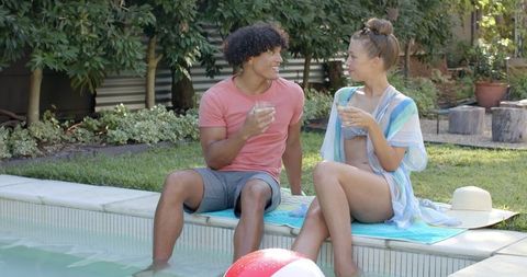 Young couple relaxing on poolside in sunny backyard setting
