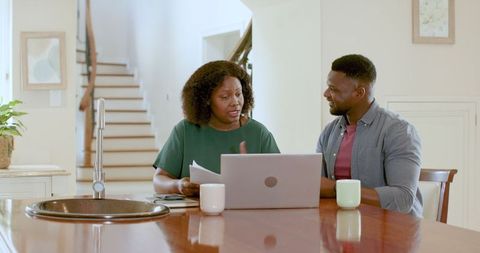 Mature Couple Discussing Finances with Laptop at Kitchen Table