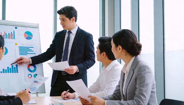 Executive presenting analytics charts to team during modern boardroom meeting with reports
