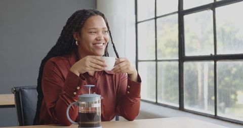 Smiling Woman Relaxing with Coffee in Modern Office Space