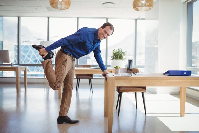Smiling executive stretching in a modern office environment. Ideal for promoting workplace wellness, healthy lifestyle, and work-life balance. Suitable for corporate wellness programs, business productivity articles, and office culture promotions.