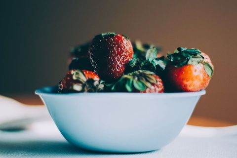 Macro bowl ripe strawberries sitting in soft natural light with shallow depth of field