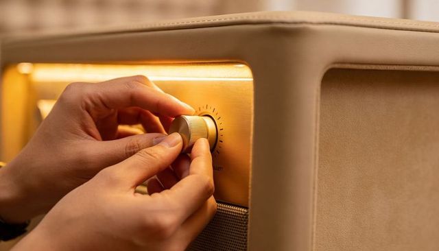 Adjusting vintage brass knob on retro speaker cabinet close-up, warm beige interior detail