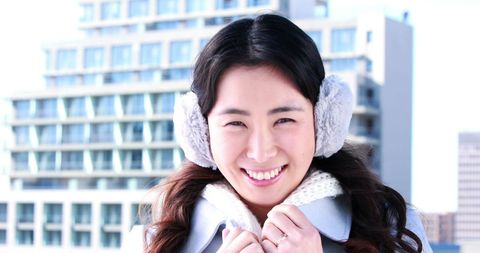 Joyful Woman Smiling in Winter Attire with Earmuffs